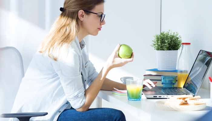 woman eating healthy while working at home